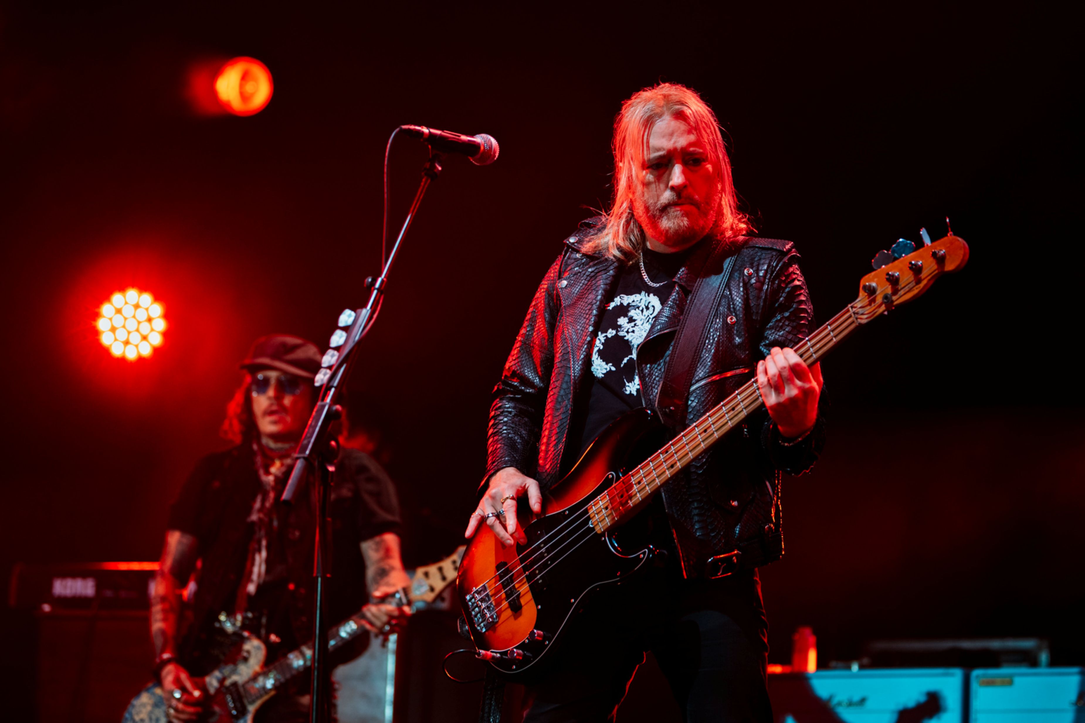 Musicians performing on stage with guitars under red lighting