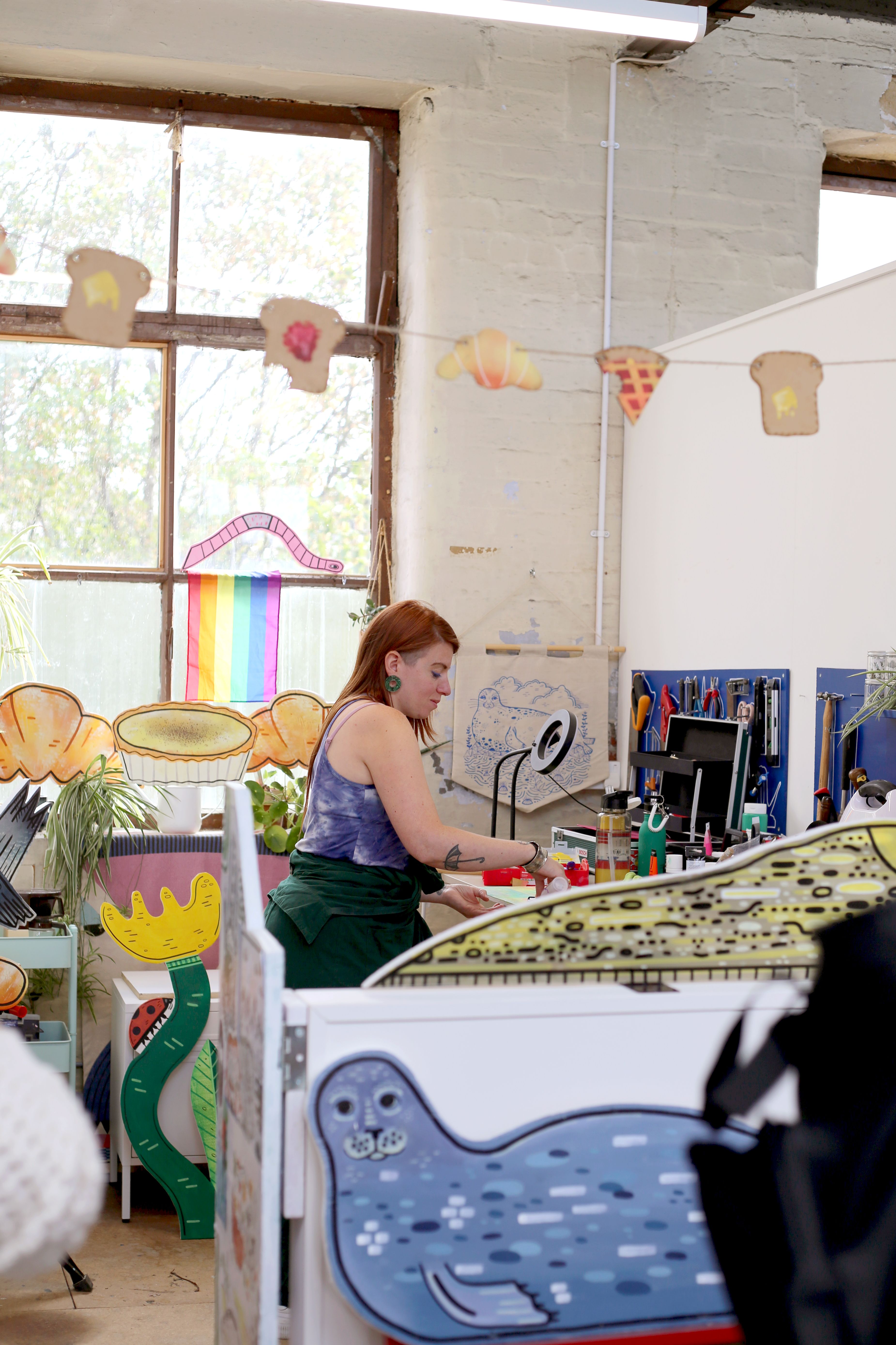 Artist painting in colourful studio with large windows