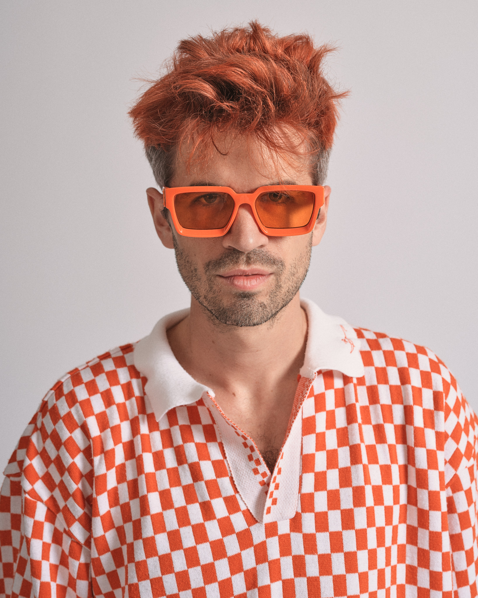 Man with red hair wearing orange sunglasses and checkered shirt