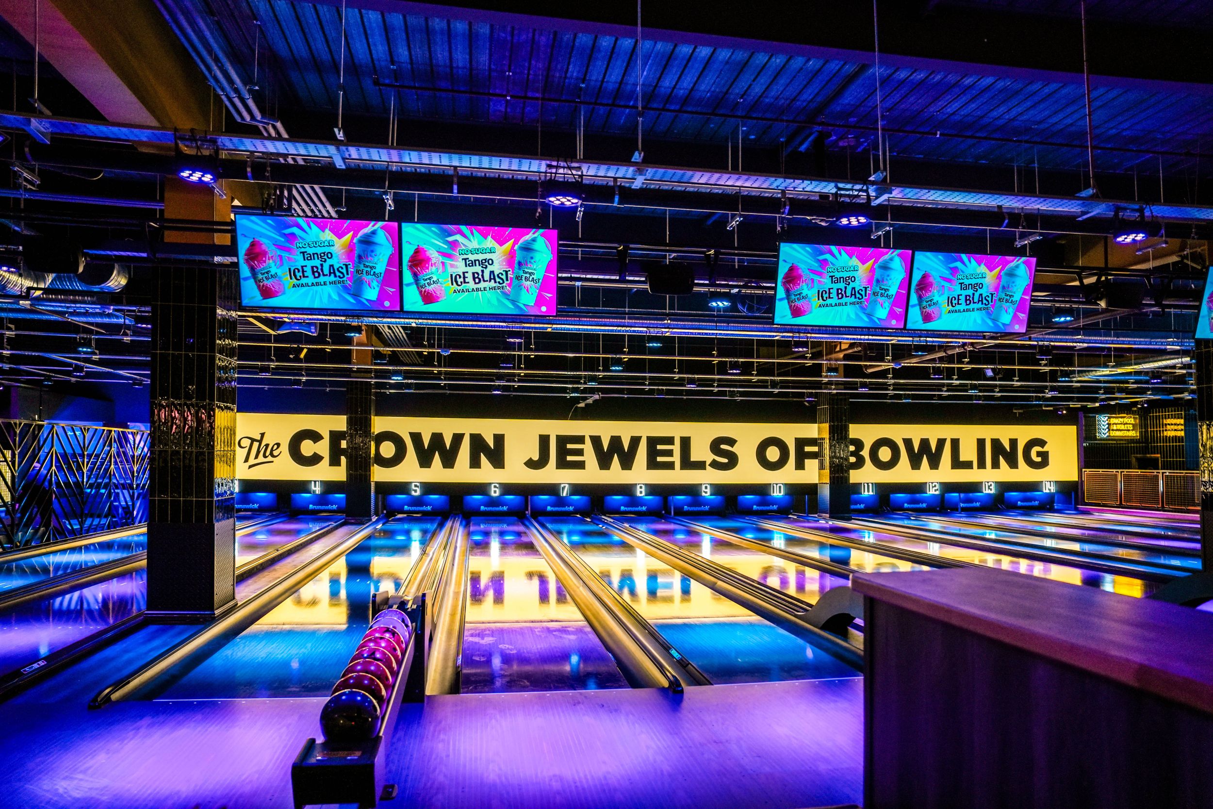Modern bowling alley with neon lights and colorful screens