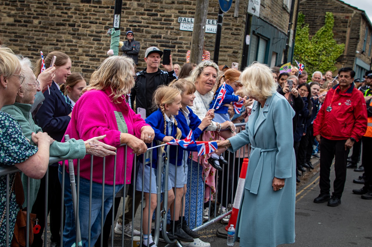 Crowd greeting woman in blue coat with UK flags in Yorkshire