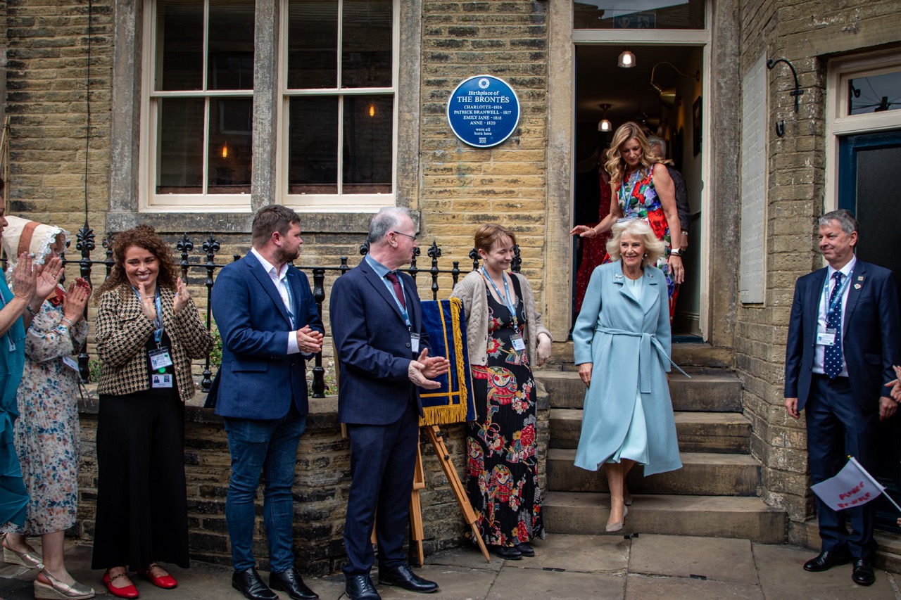 Group of people outside a historic stone building with plaque