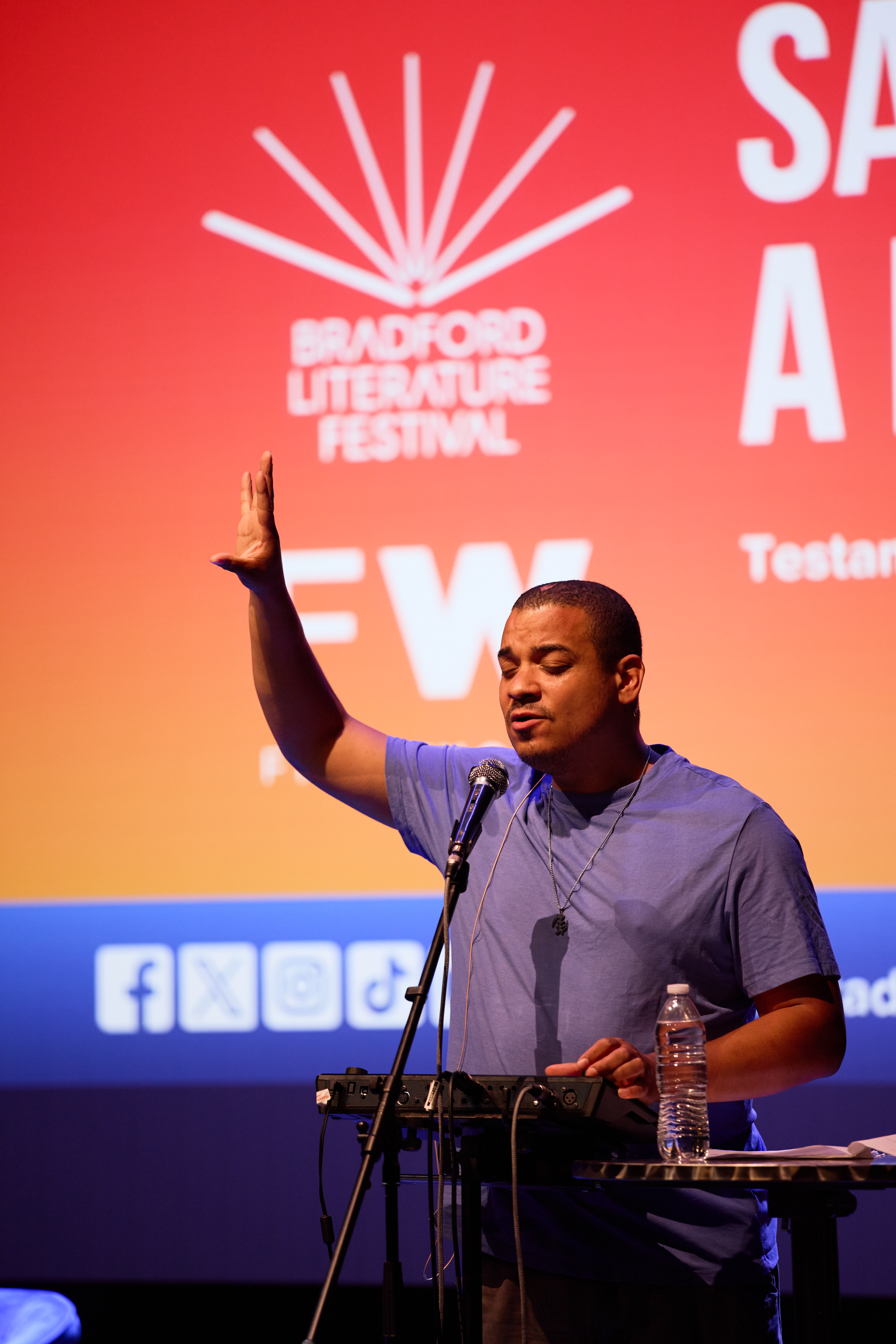 Man speaking at Bradford Literature Festival with raised hand