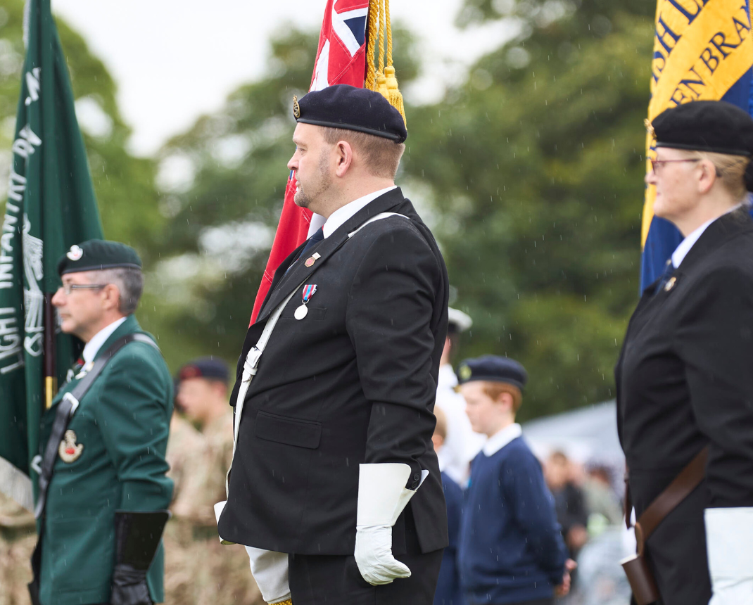 Uniformed people in a ceremonial parade with flags