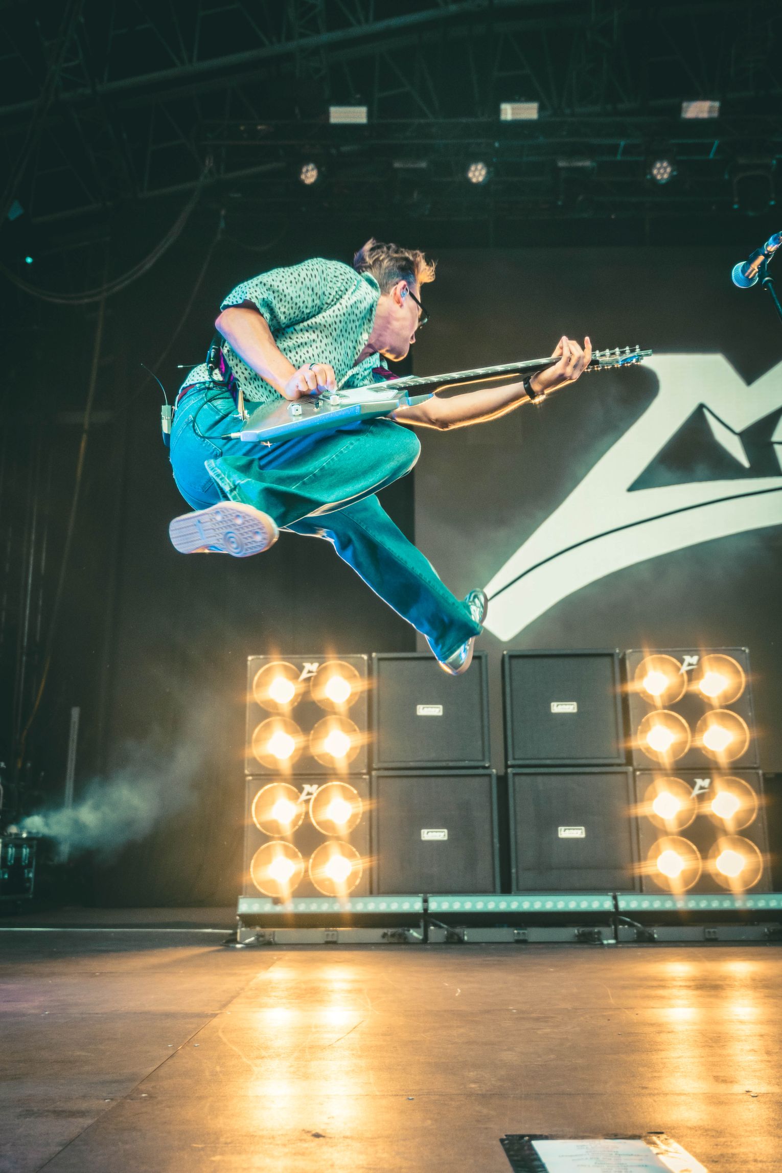 Guitarist mid-air at outdoor music festival stage