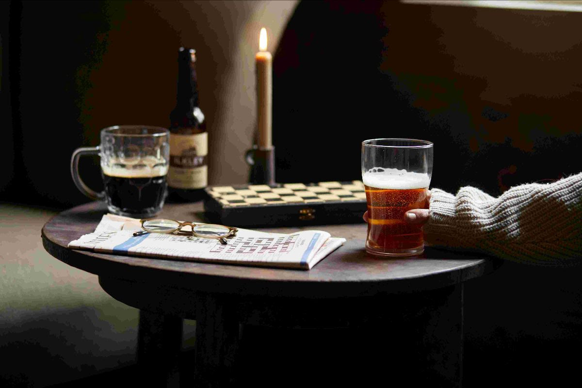 Cozy pub scene with beer, newspaper, and candlelight
