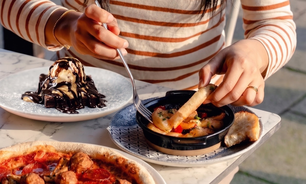 Person enjoying tapas with bread at a sunlit outdoor table