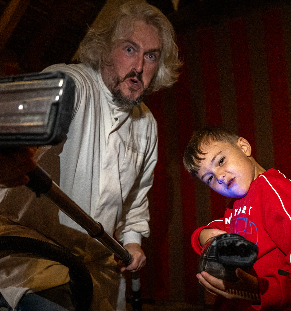Man demonstrating historic vacuum cleaner to intrigued child