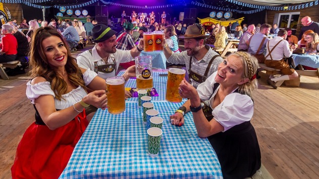 People in traditional Bavarian attire enjoying beer at a festival