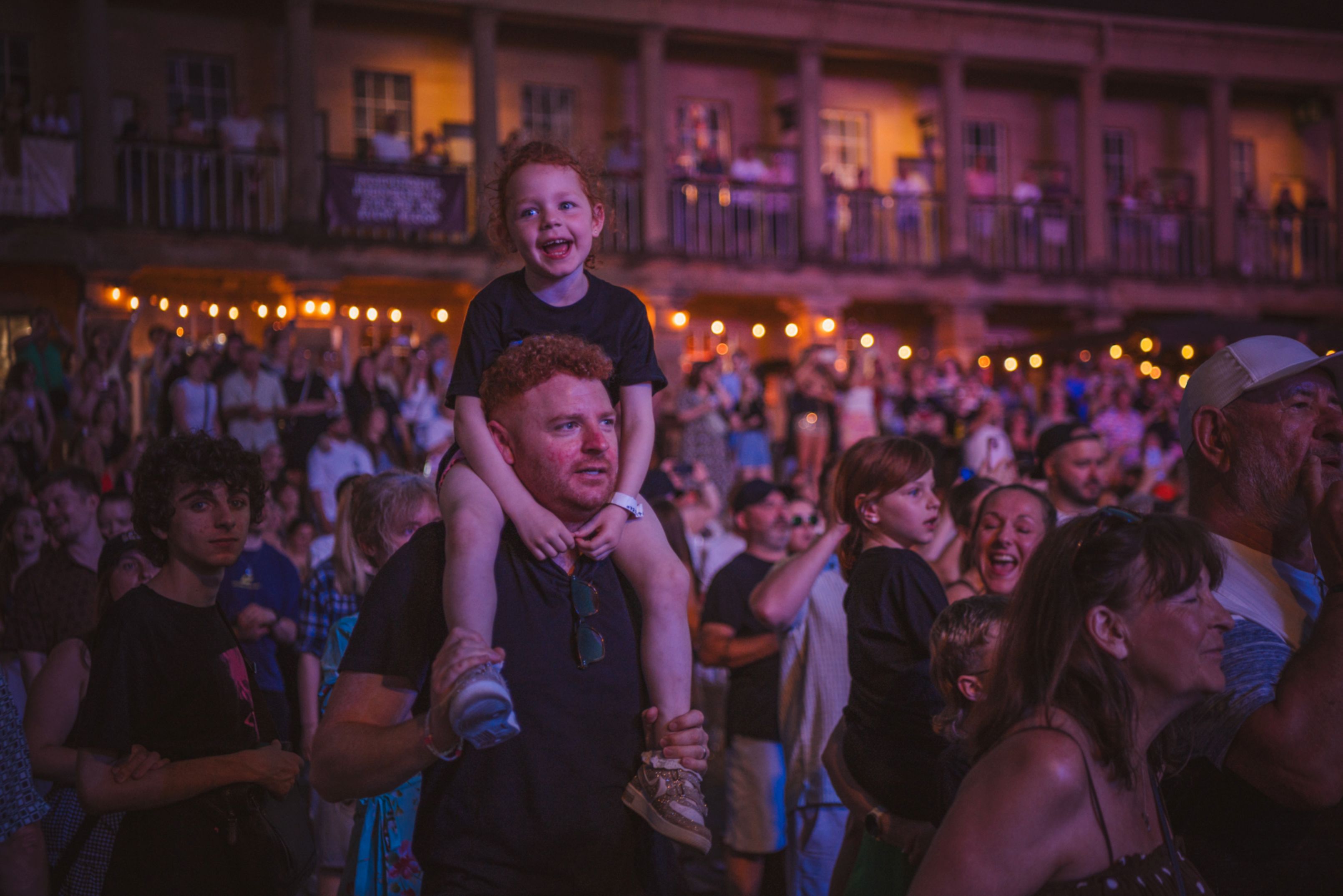 Crowd enjoying outdoor concert at night with string lights