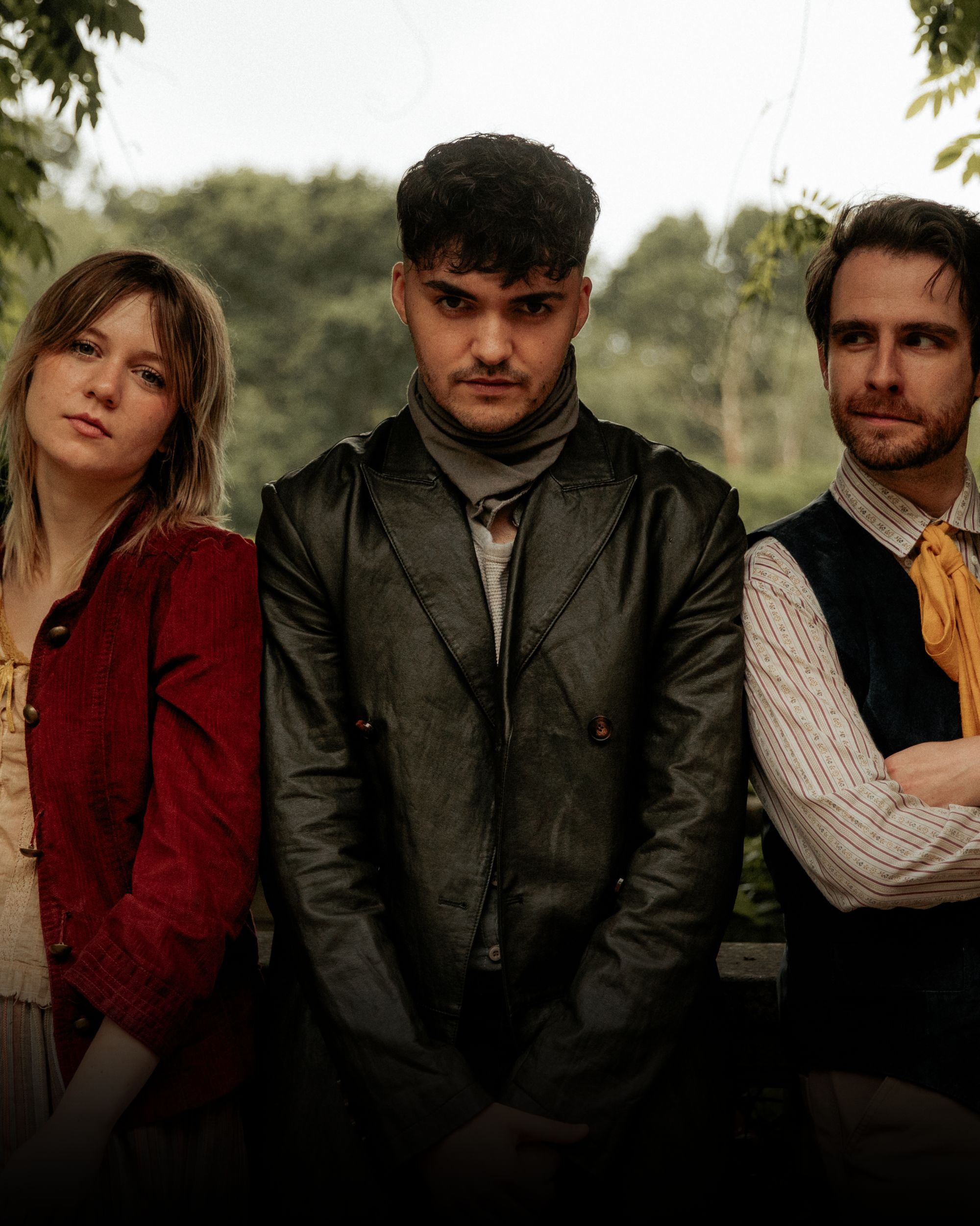 Three people in vintage clothing standing in a leafy garden