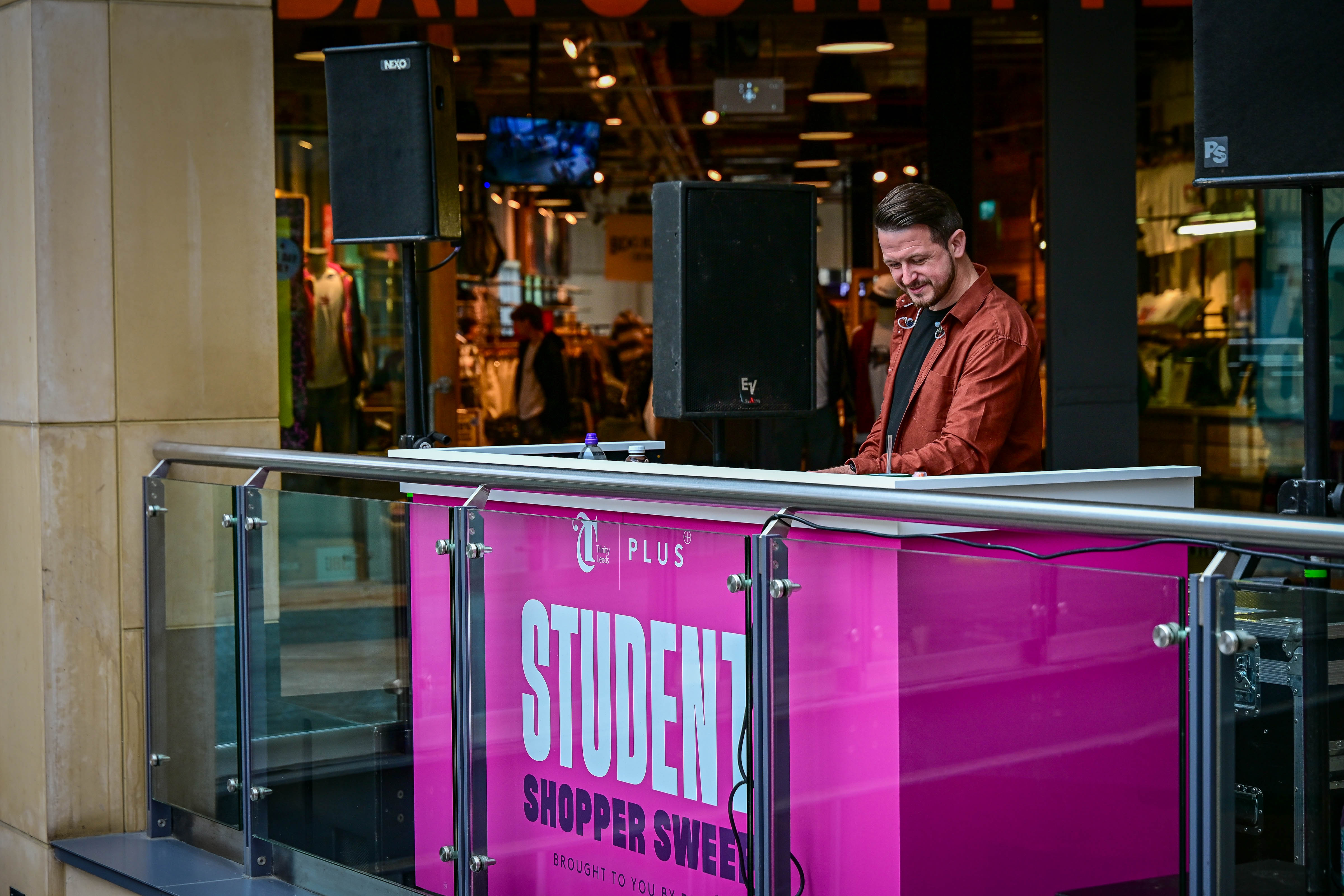 DJ in brown jacket performing on shopping centre balcony