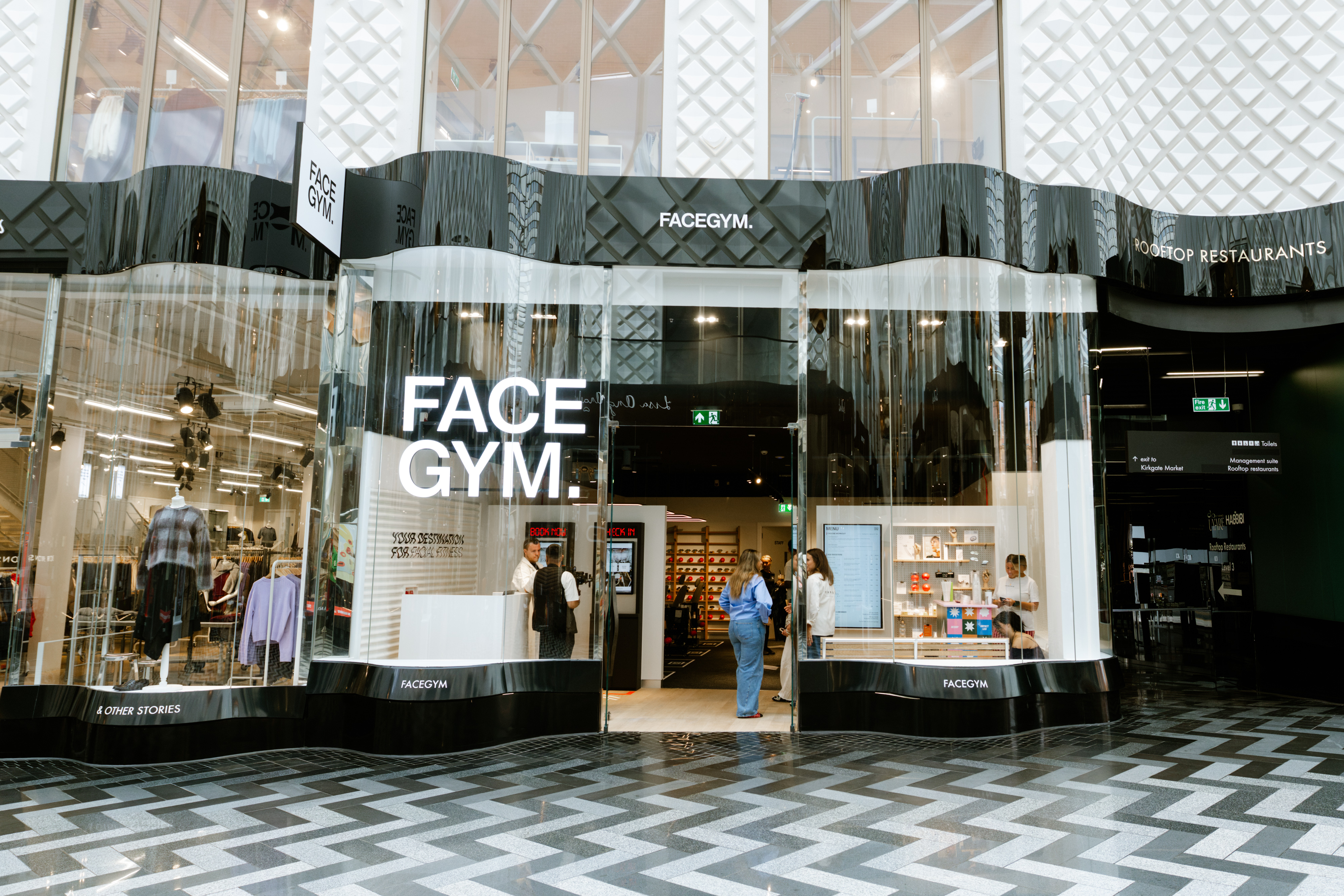 Modern shopping centre with glass facade and various retail stores