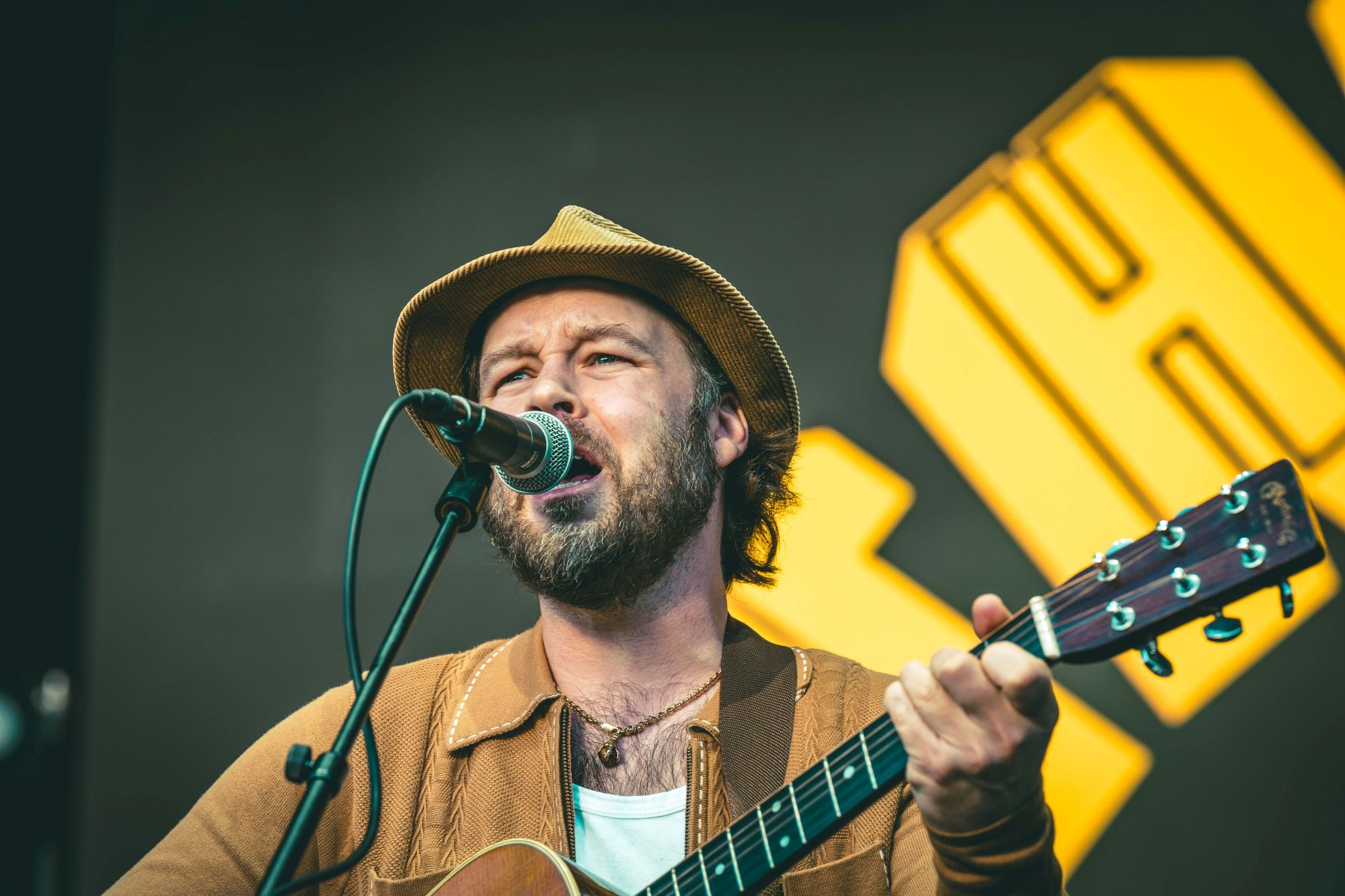 Musician wearing a hat playing guitar and singing on stage