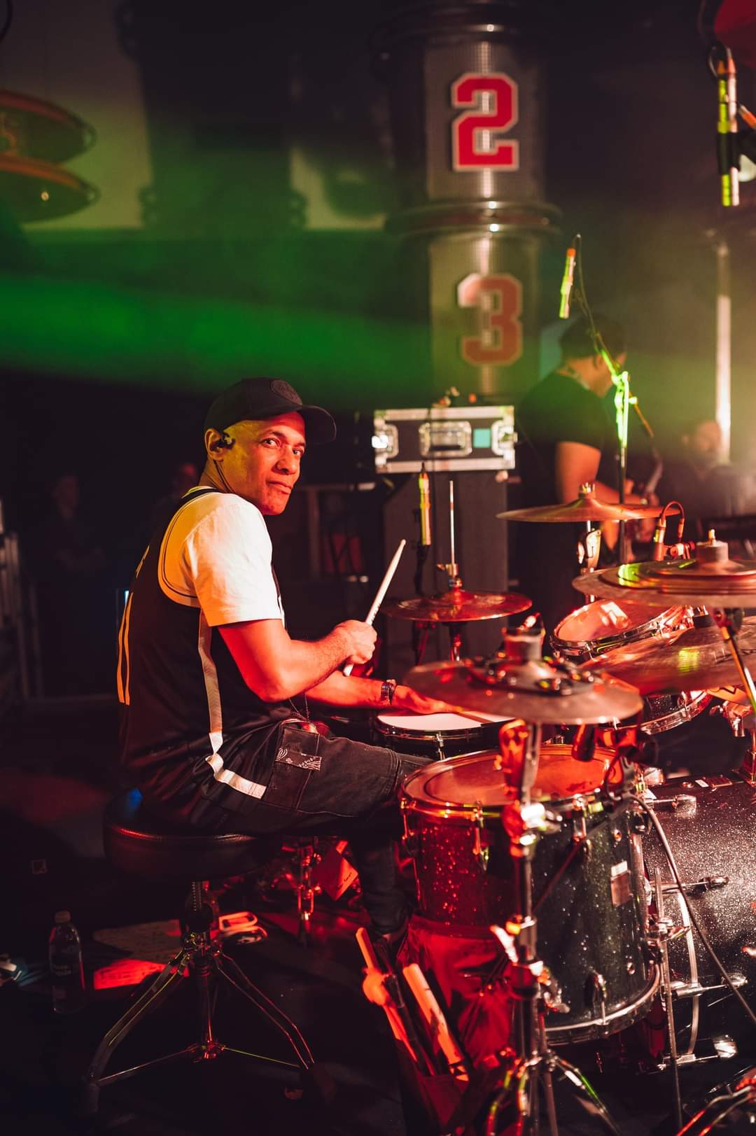 Drummer performing on stage with vibrant lights and equipment