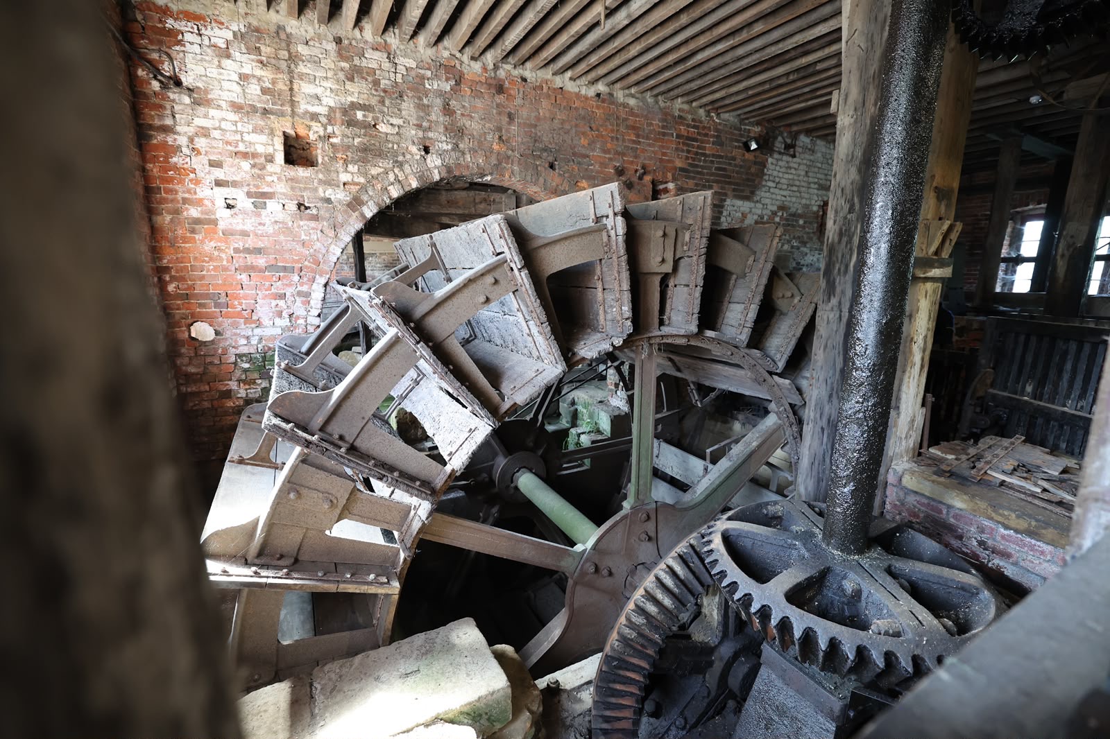 Historic watermill interior with large wooden wheel and brick walls