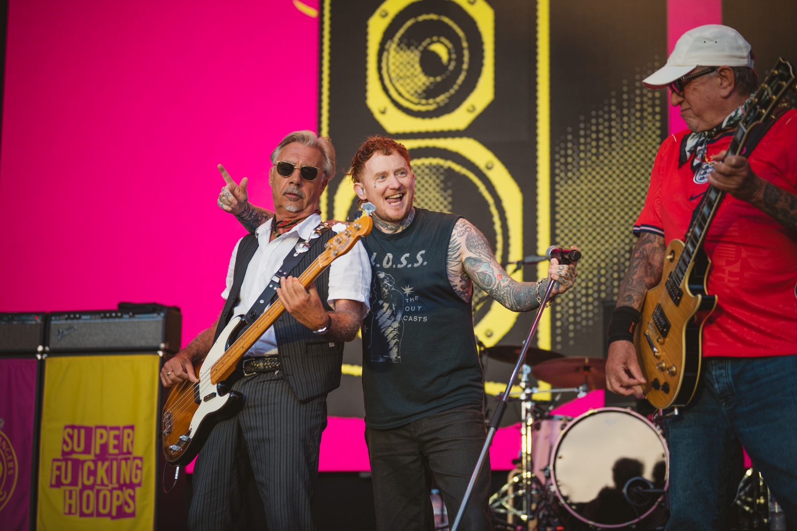 Three musicians performing on stage with electric guitars
