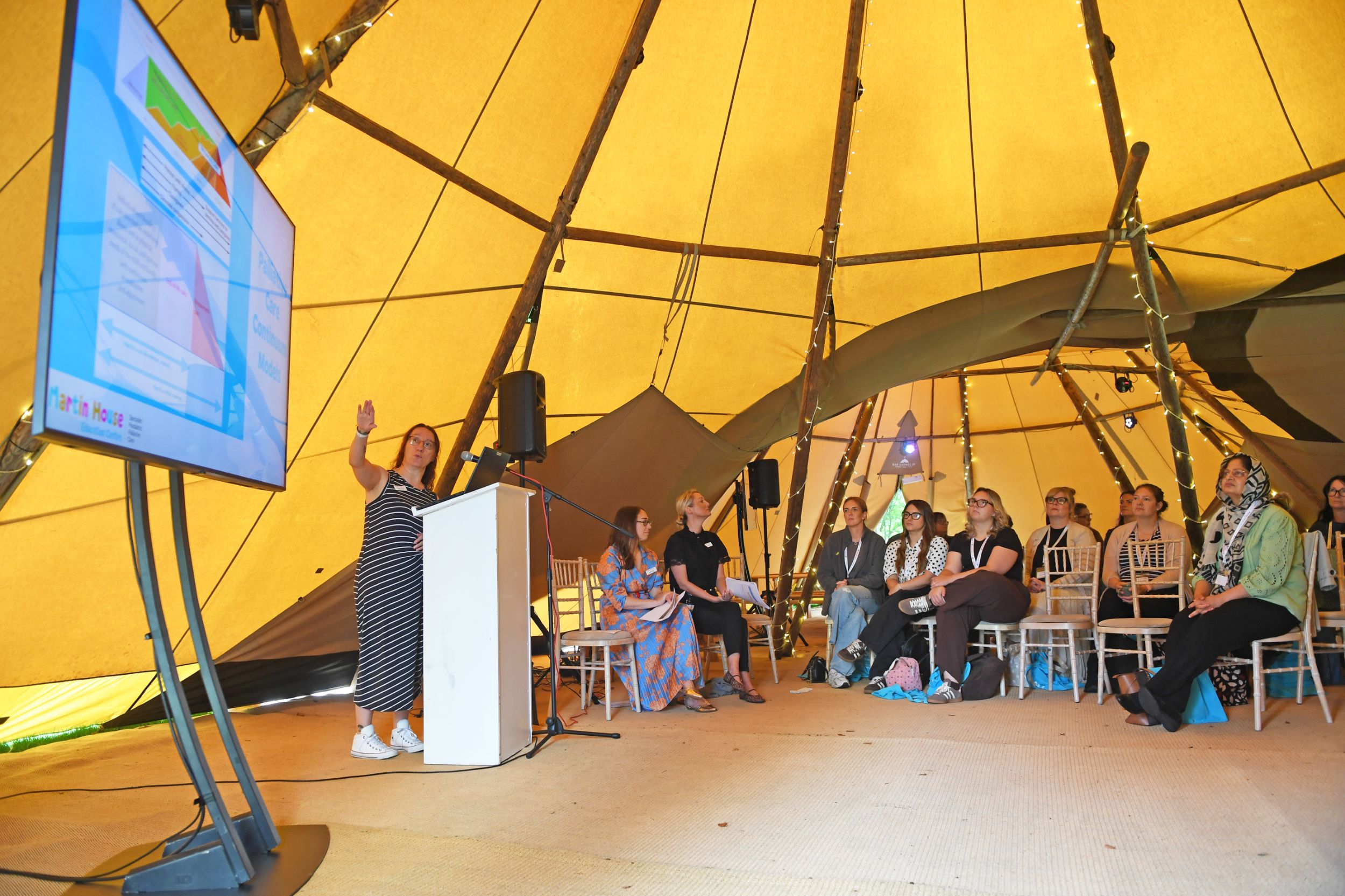 Group of people attending a presentation inside a tipi tent