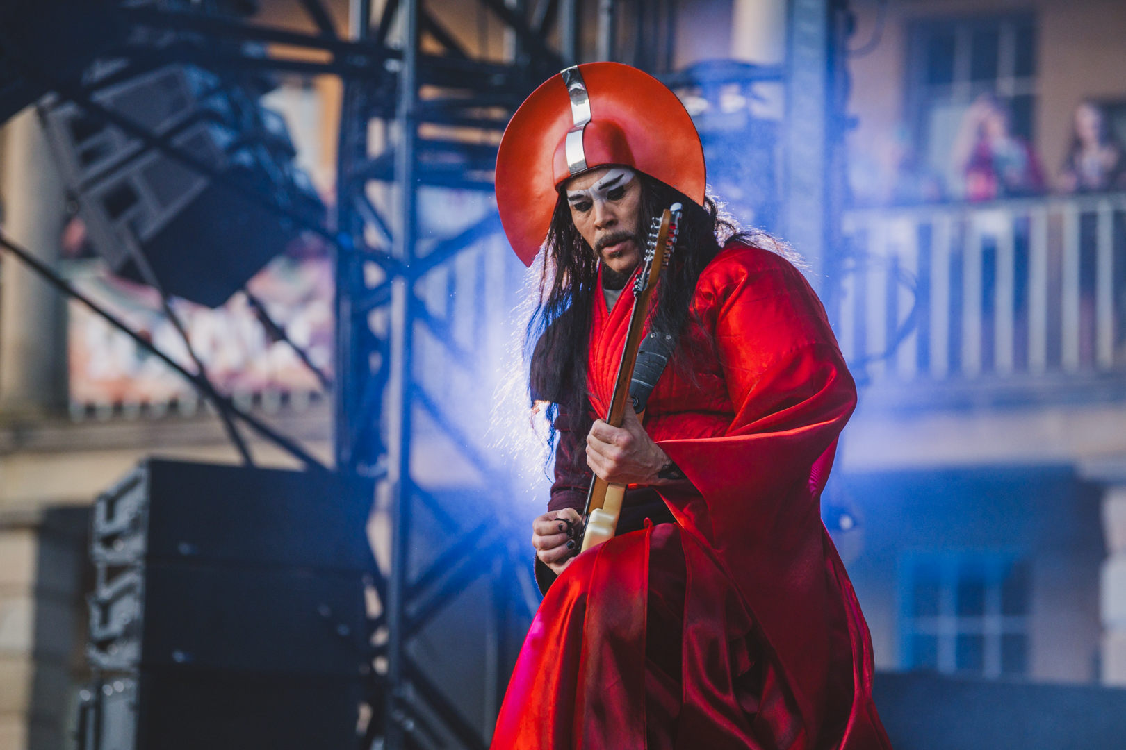 Musician in red costume playing guitar on outdoor stage