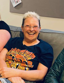 Person smiling on a sofa wearing a graphic T-shirt