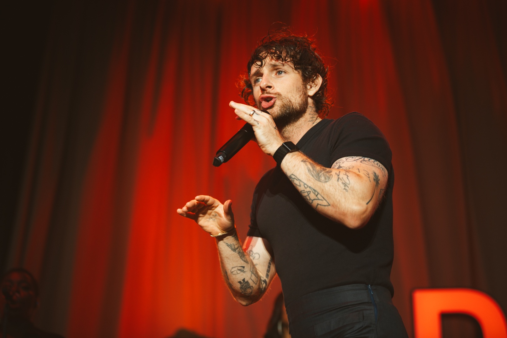 Tattooed man performing on stage with red lighting