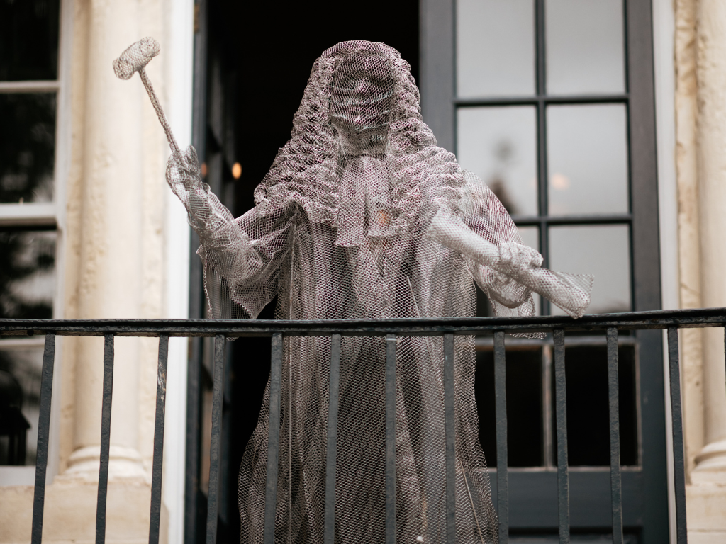 Wire sculpture of a judge with gavel on historic balcony