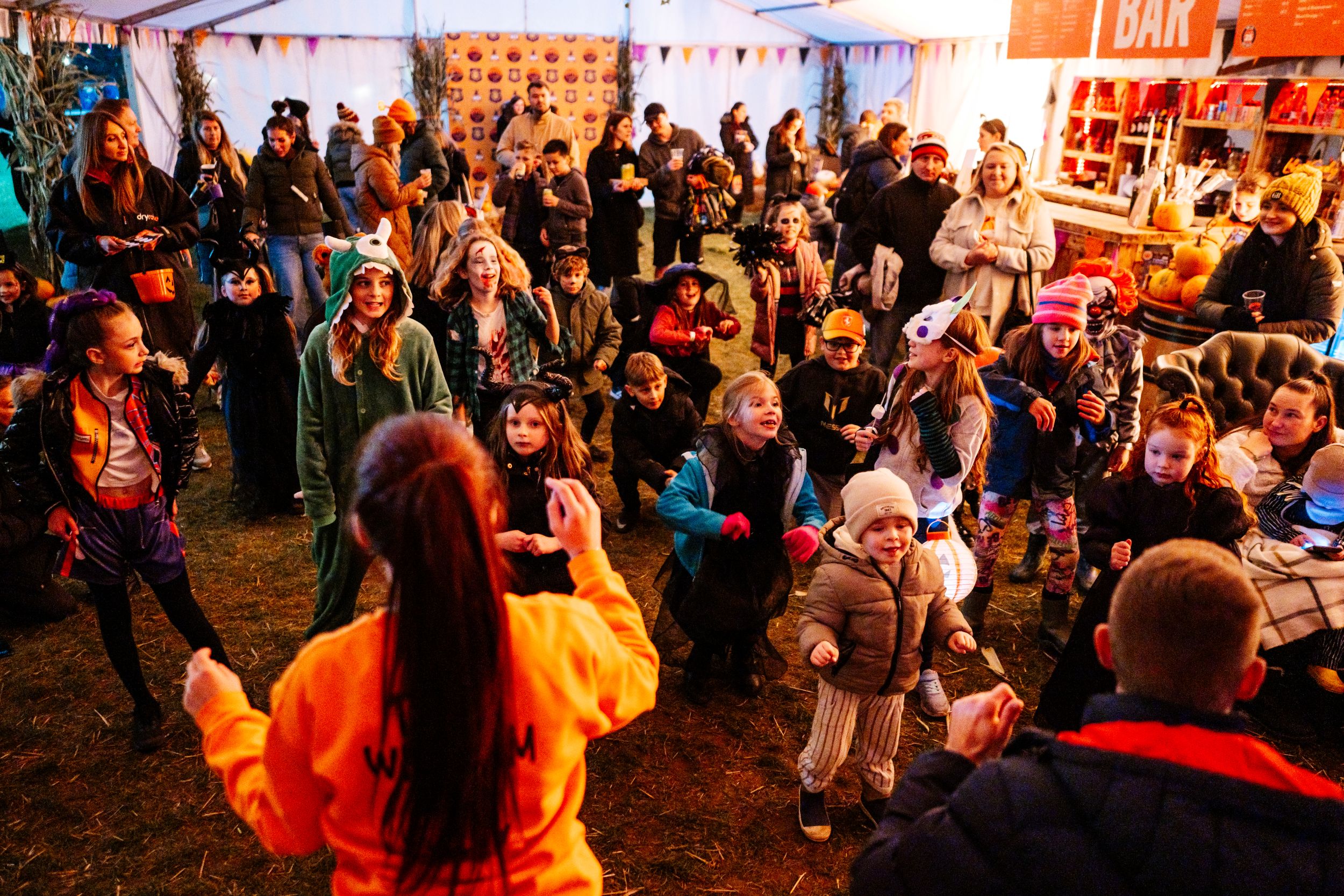 Children in costumes dancing at a lively Halloween festival
