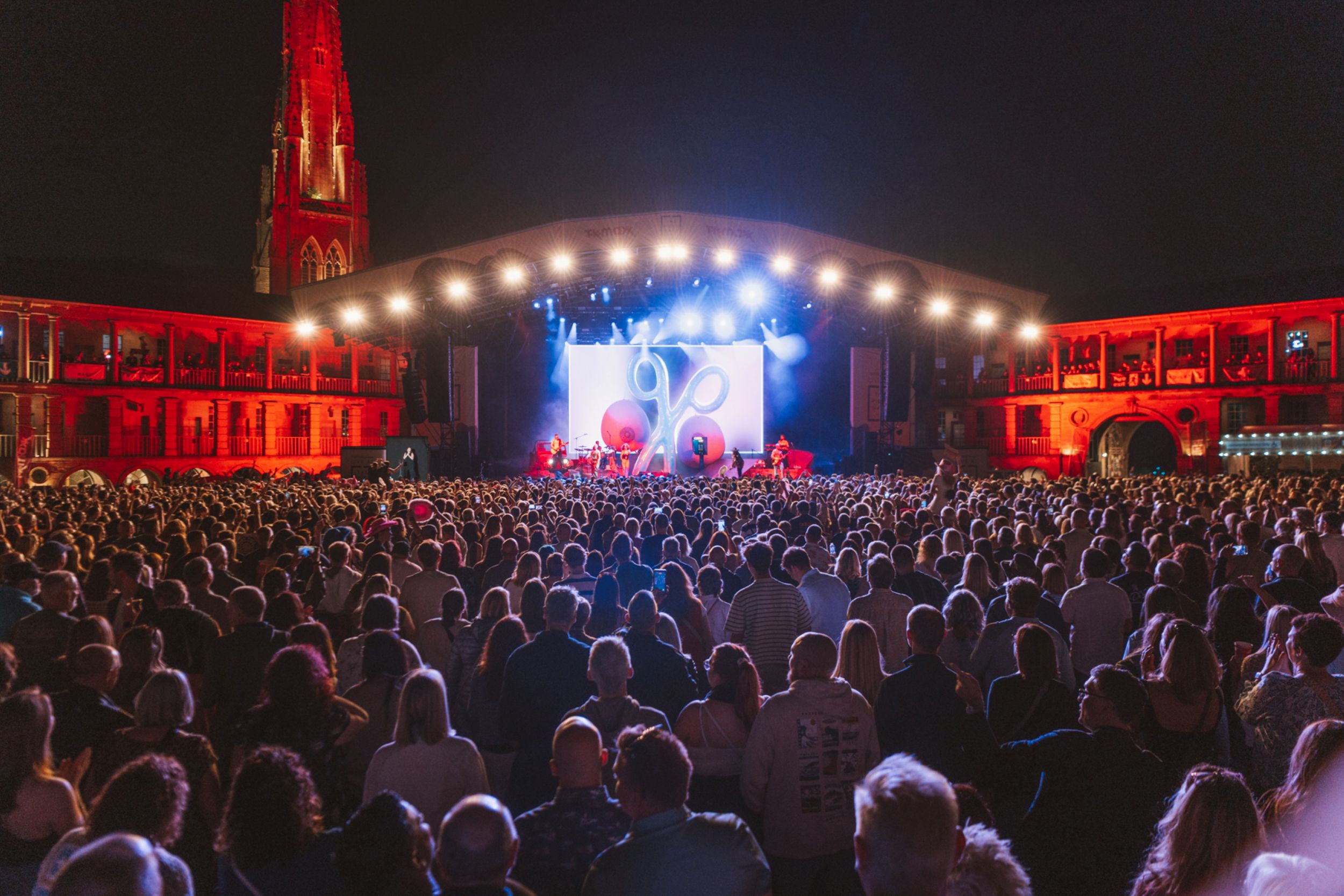 Night concert at illuminated outdoor venue with large crowd