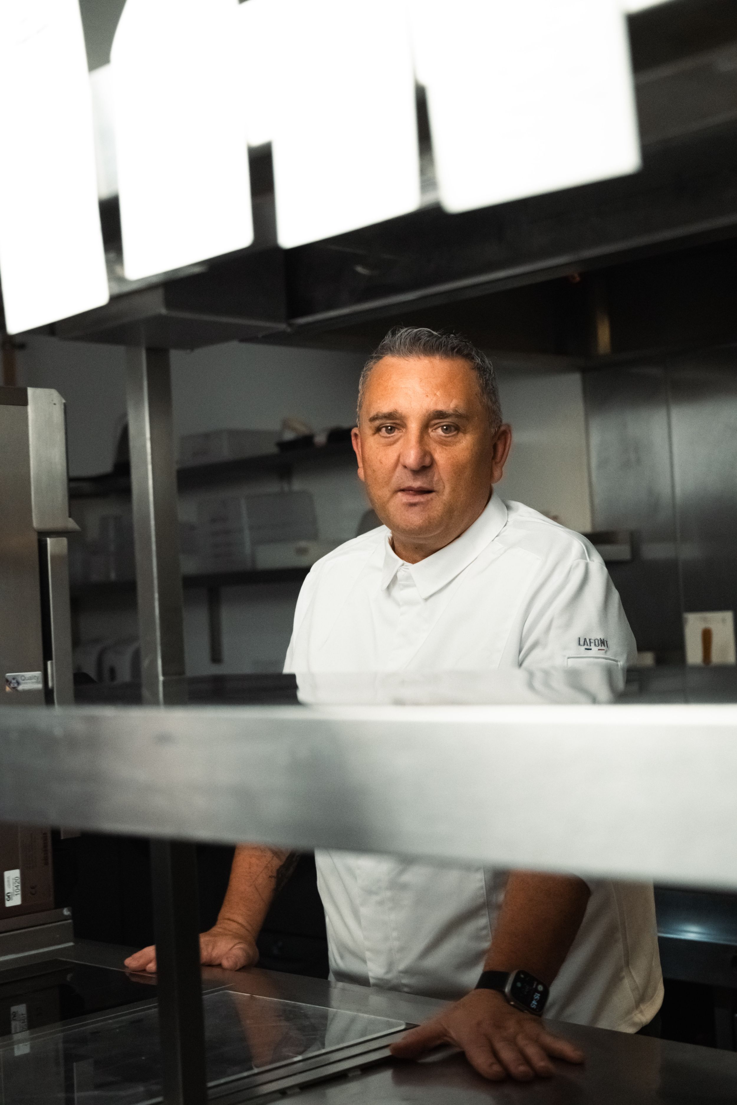 Chef in white uniform stands in a modern stainless steel kitchen