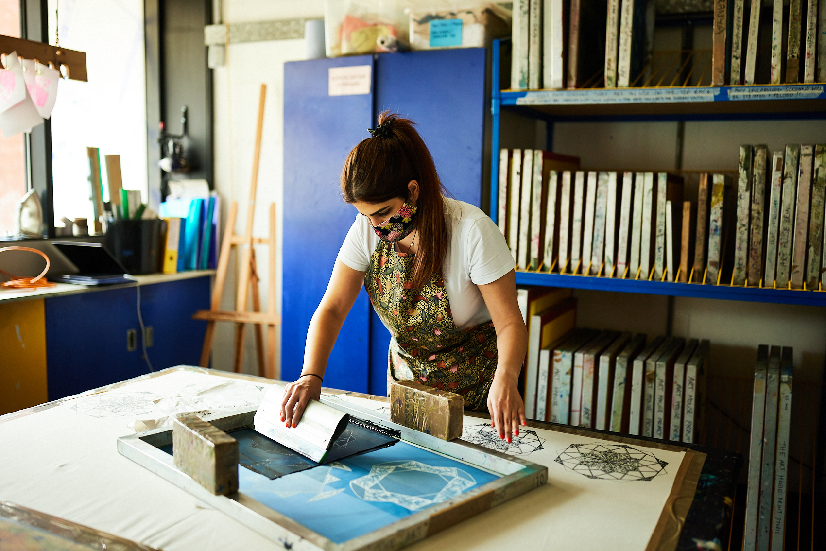 Woman screen printing in art studio with colourful apron