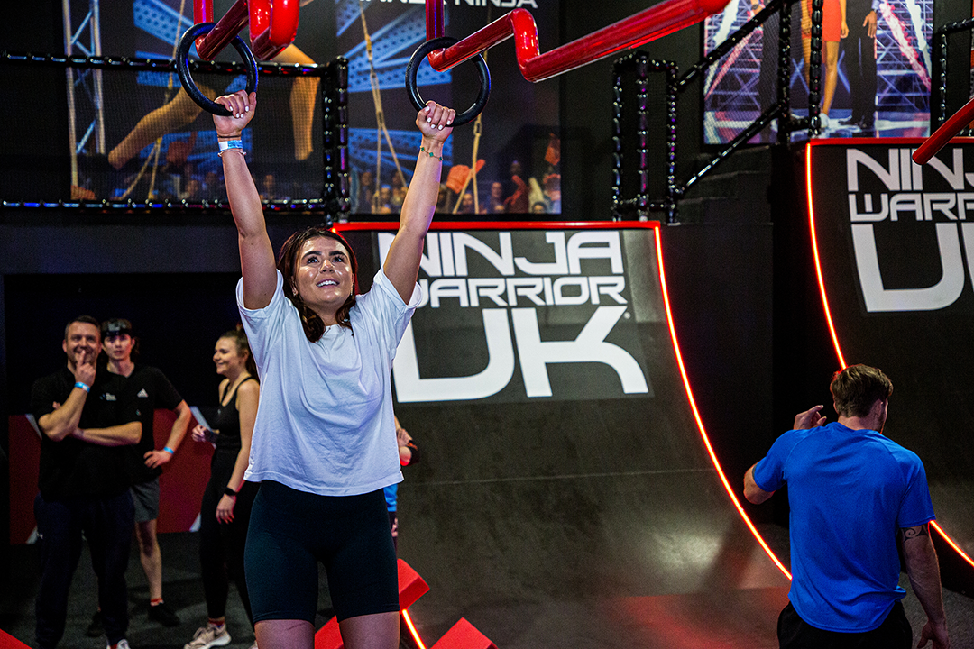 Woman in white shirt on obstacle course in indoor arena