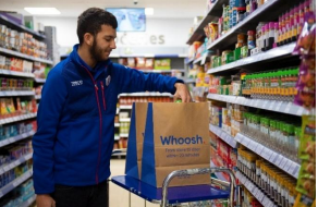 Store employee in uniform placing items in delivery bag