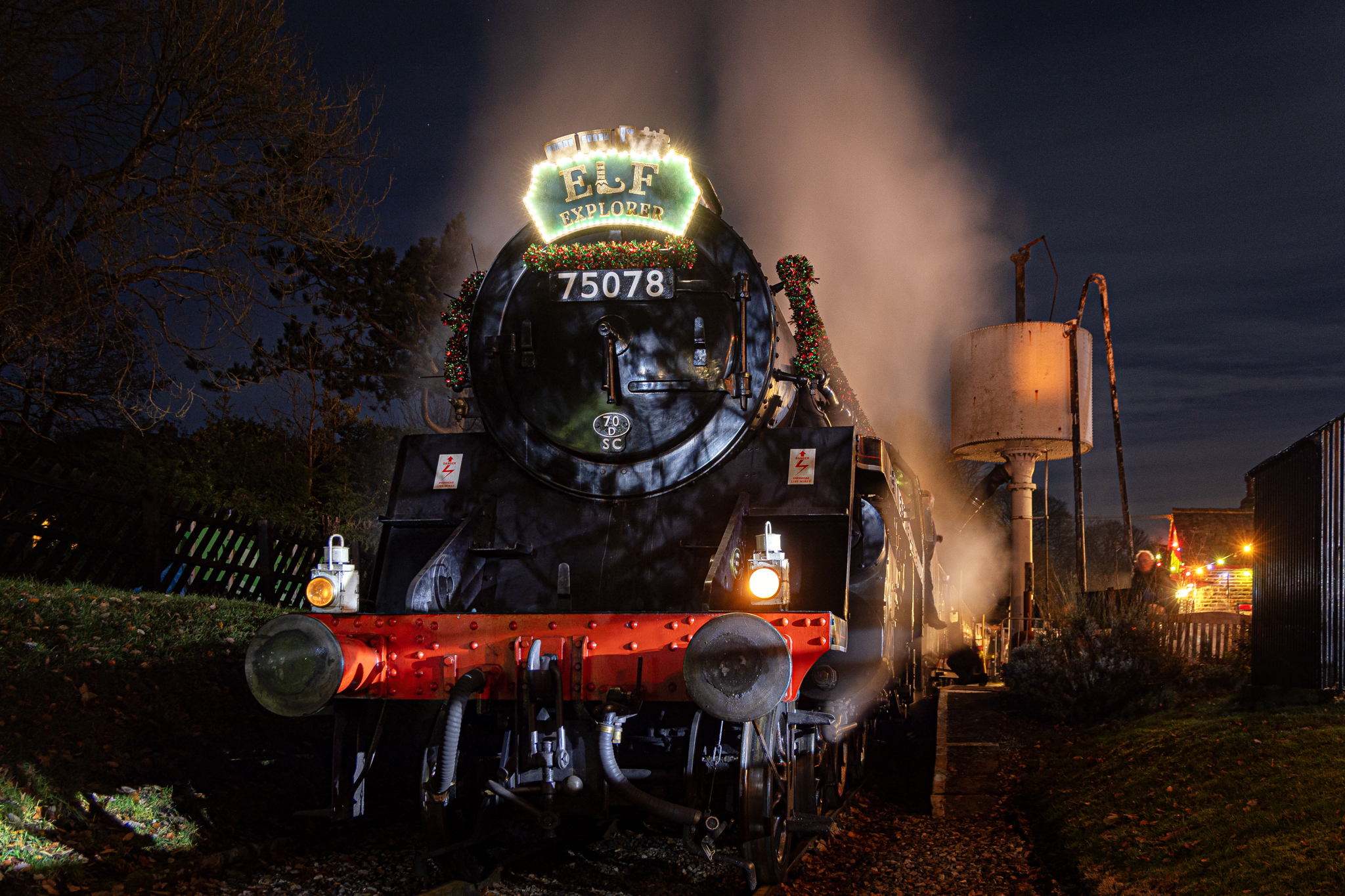 Historic steam train decorated with Christmas lights at night