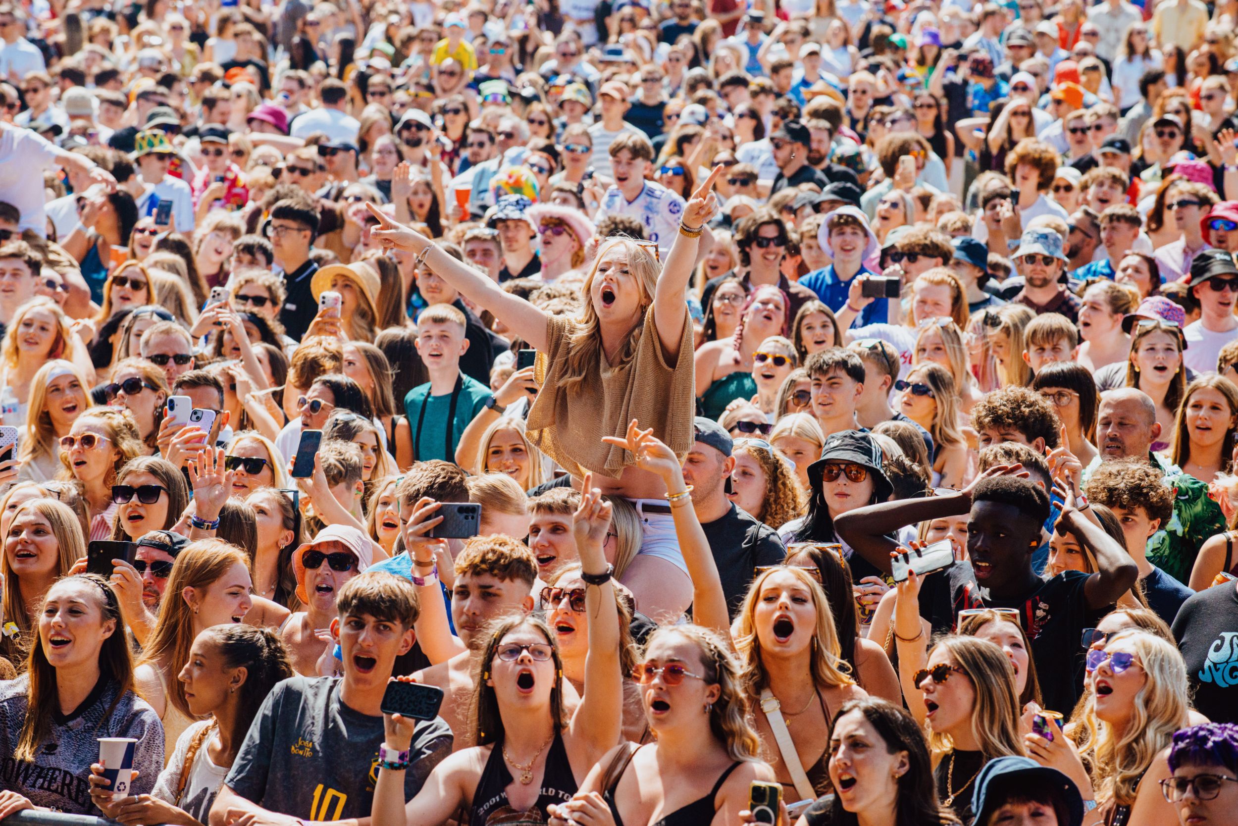 Large crowd at a lively outdoor festival with cheering people