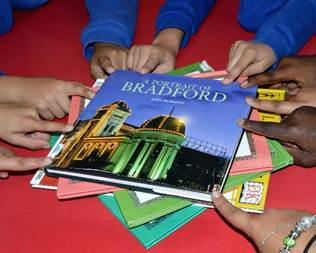 Children's hands reaching for a book titled 'A Portrait of Bradford'