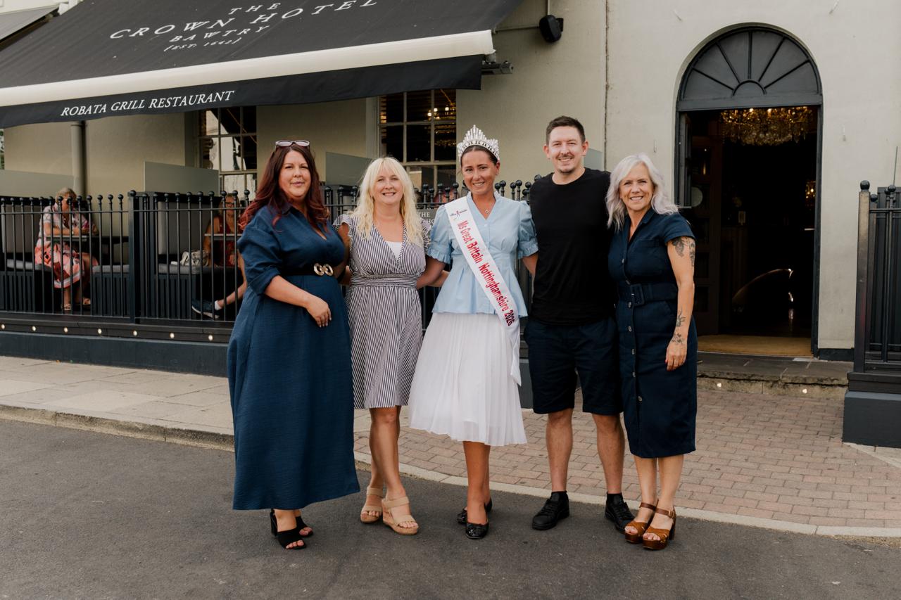 Group of five people smiling outside the Crown Hotel entrance