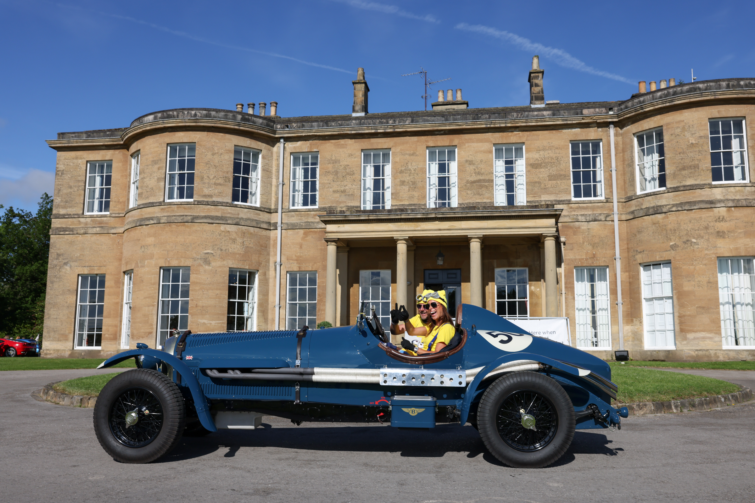 Vintage blue car in front of Georgian mansion with columns