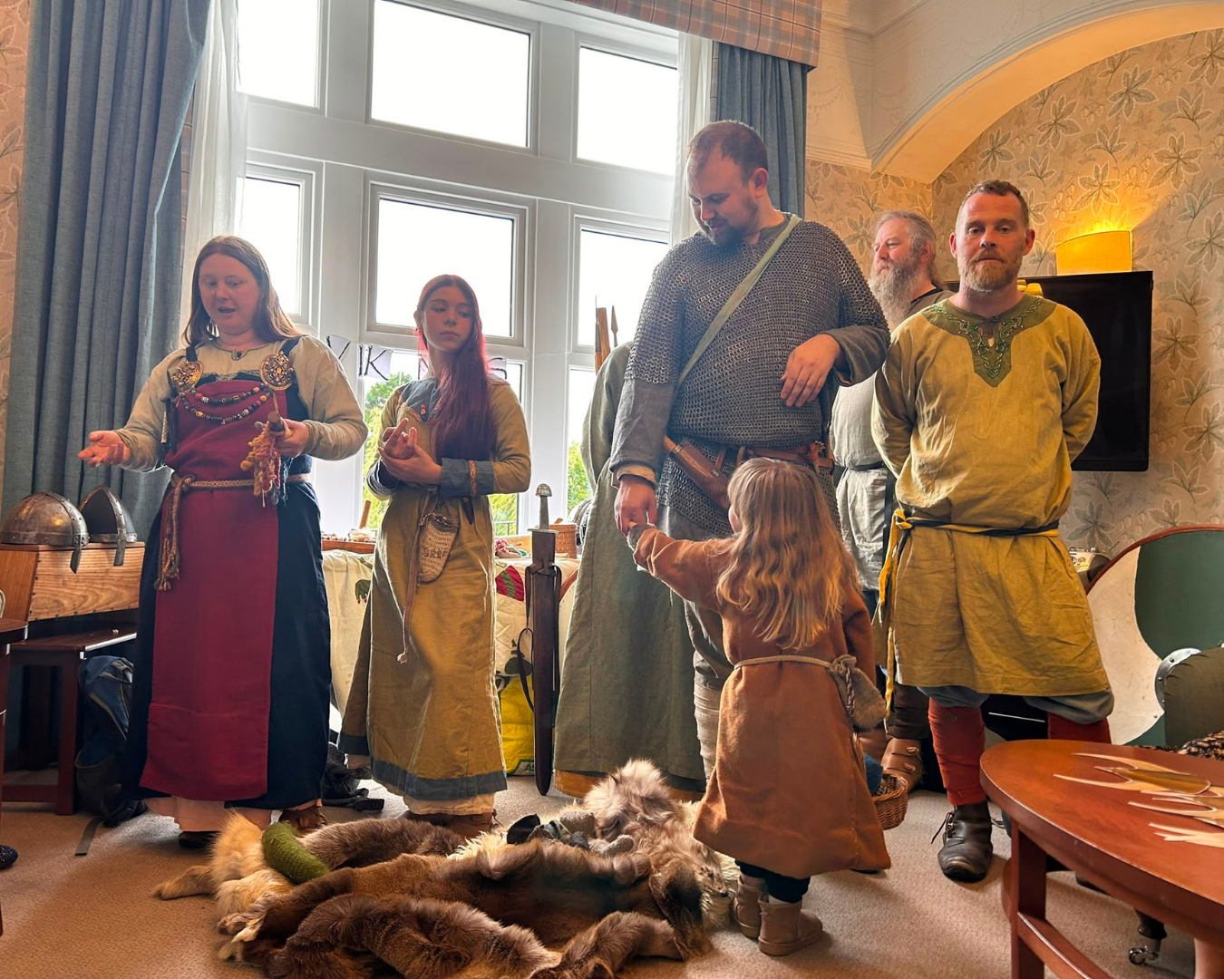 Group in Viking attire inside room with large windows