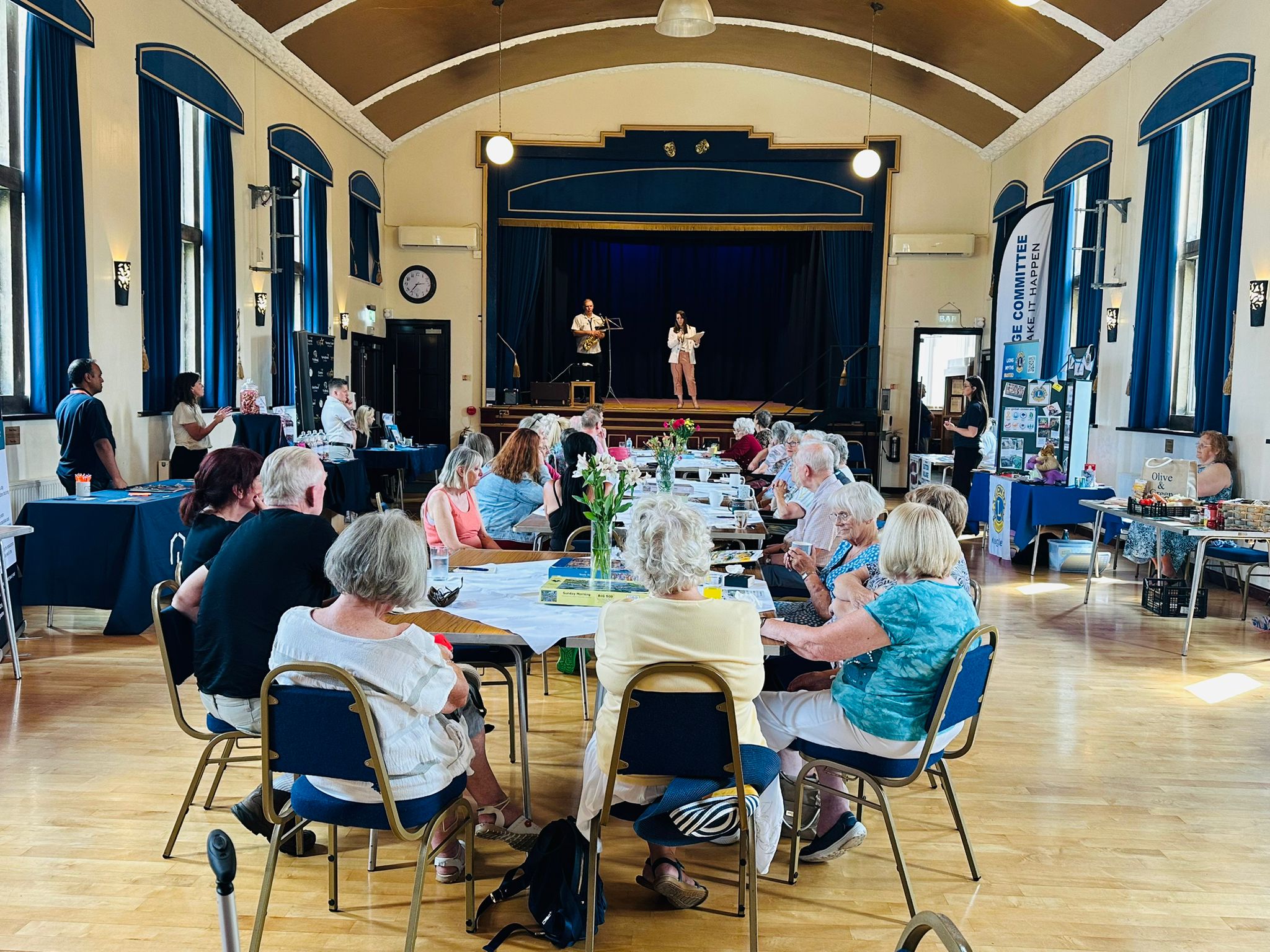 Community gathering in historic hall with stage performance