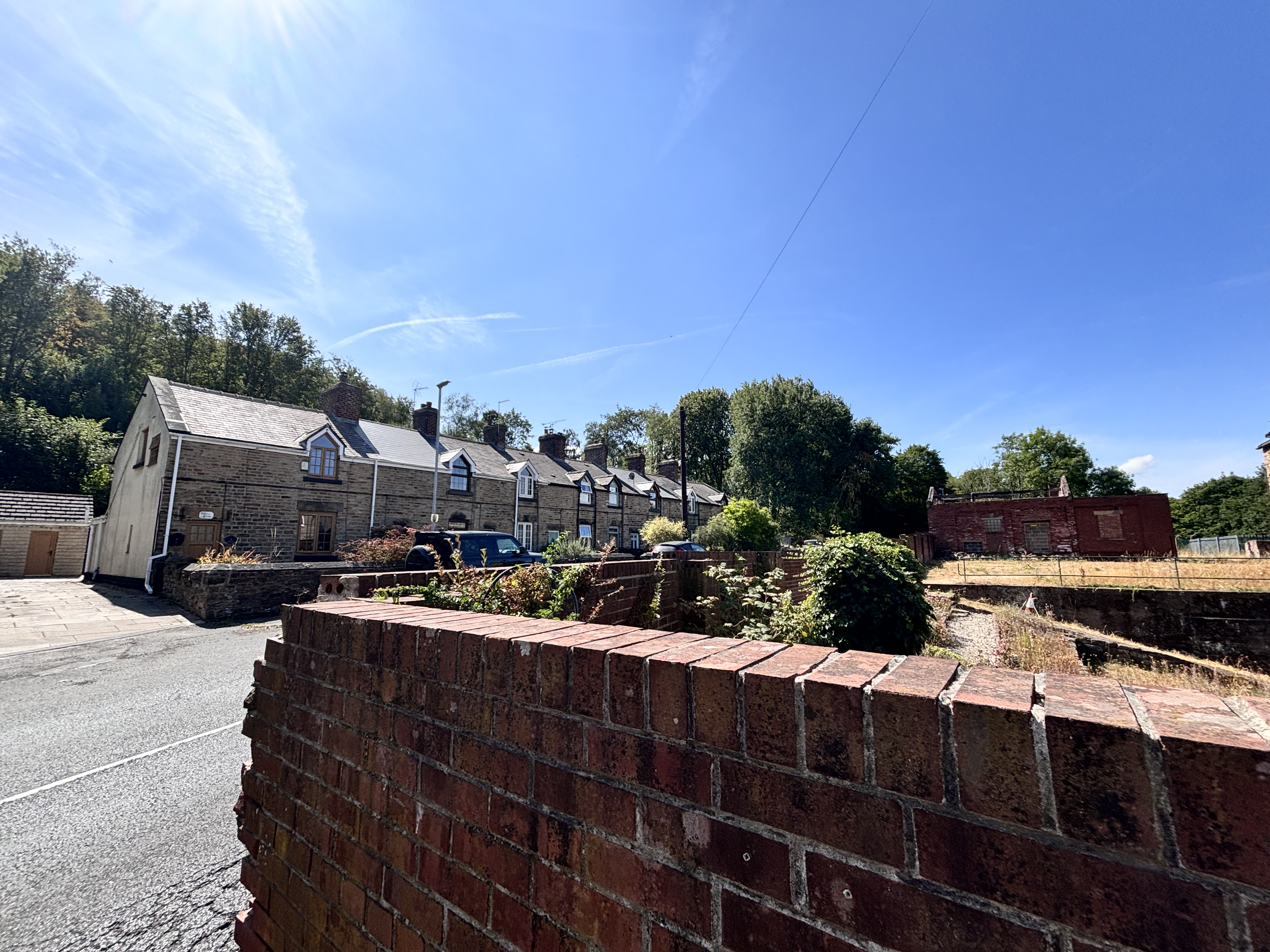 Row of quaint stone cottages with sloped roofs under a sunny blue sky