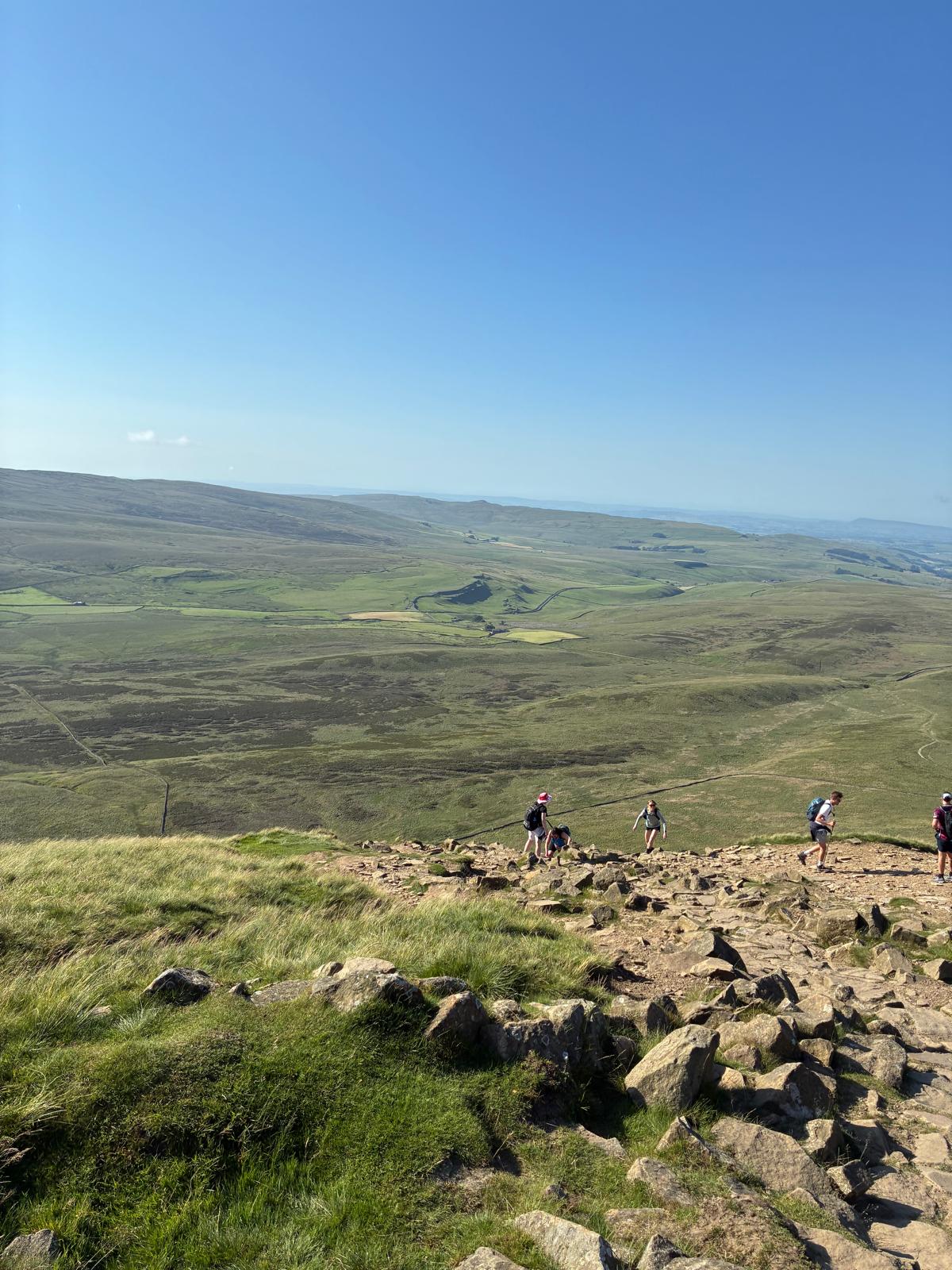 Hikers ascending a rocky path on a sunny day in the Yorkshire Dales