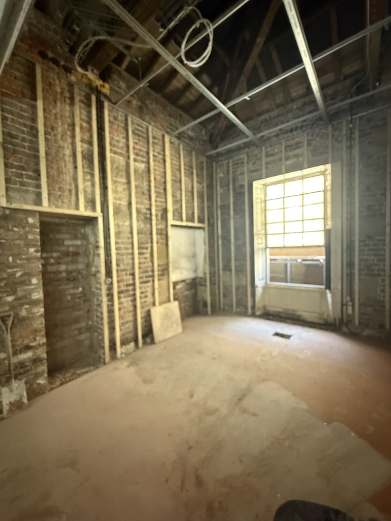 Unfinished rustic room with exposed brick walls and wooden beams