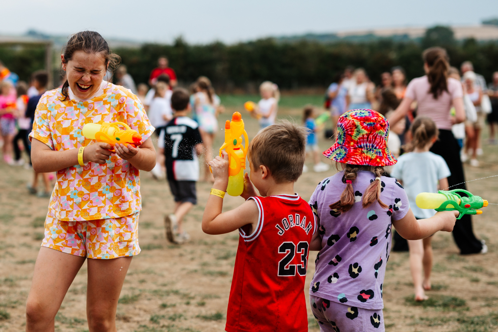 Children playing with water pistols at a lively outdoor festival