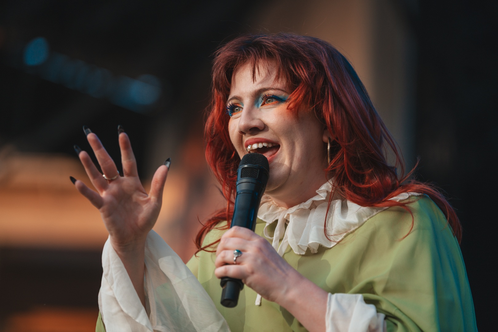 Woman with red hair performing on stage with microphone