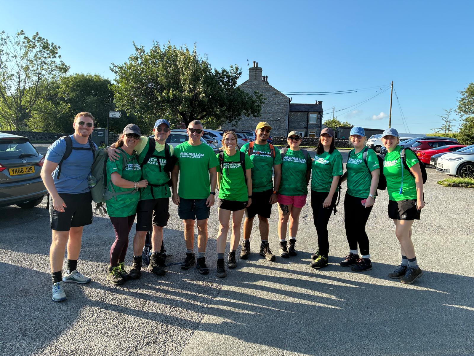 Group of hikers in green shirts standing in a sunny car park