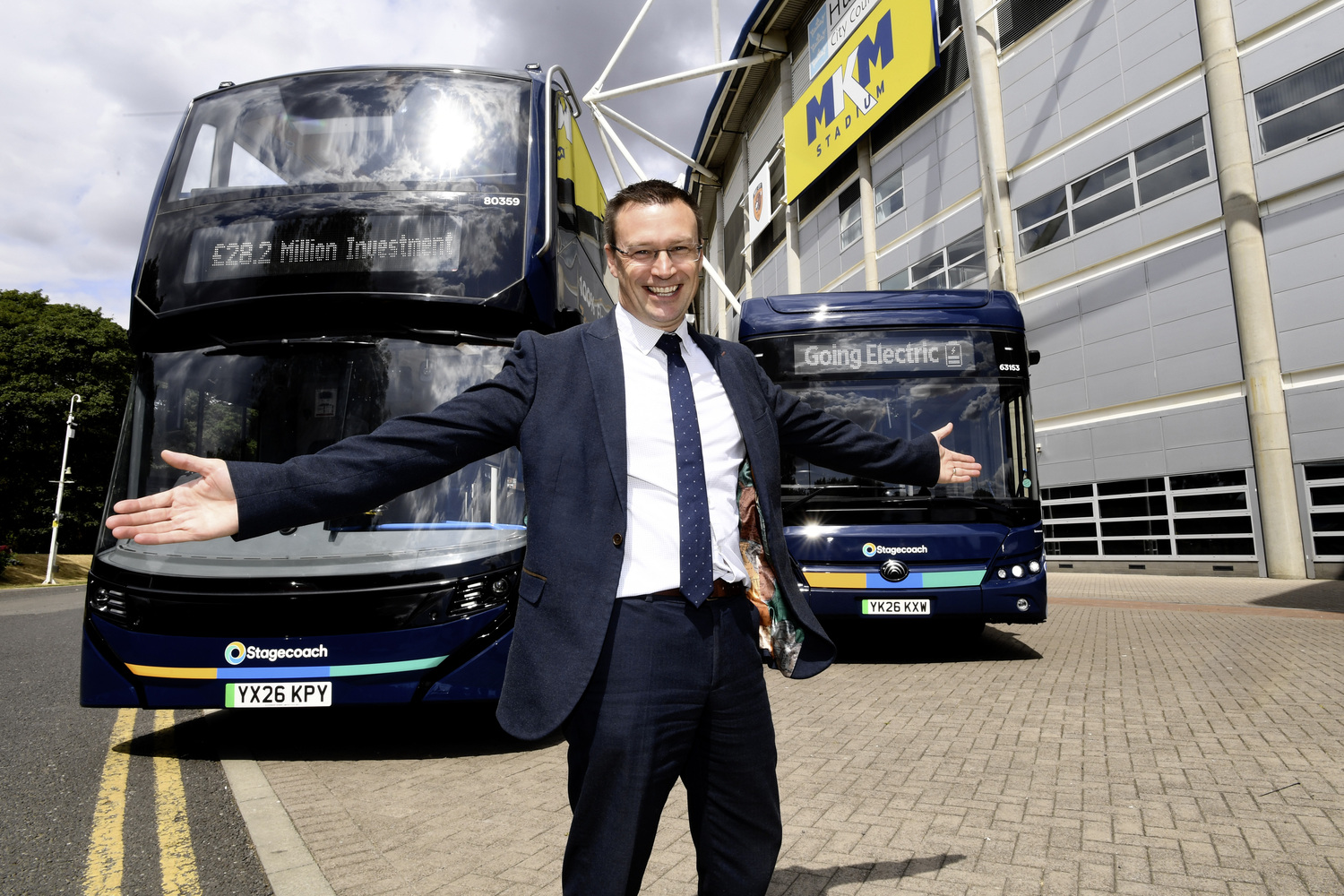 Man in suit with electric buses outside modern building