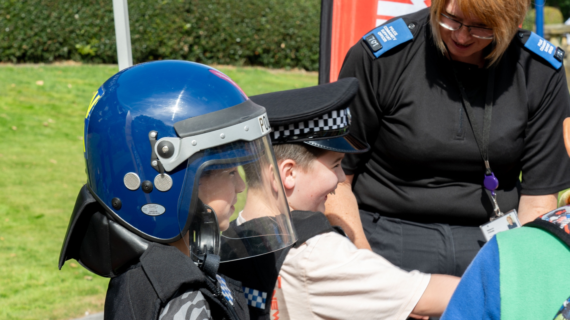 Children wearing police helmets interacting with a community officer