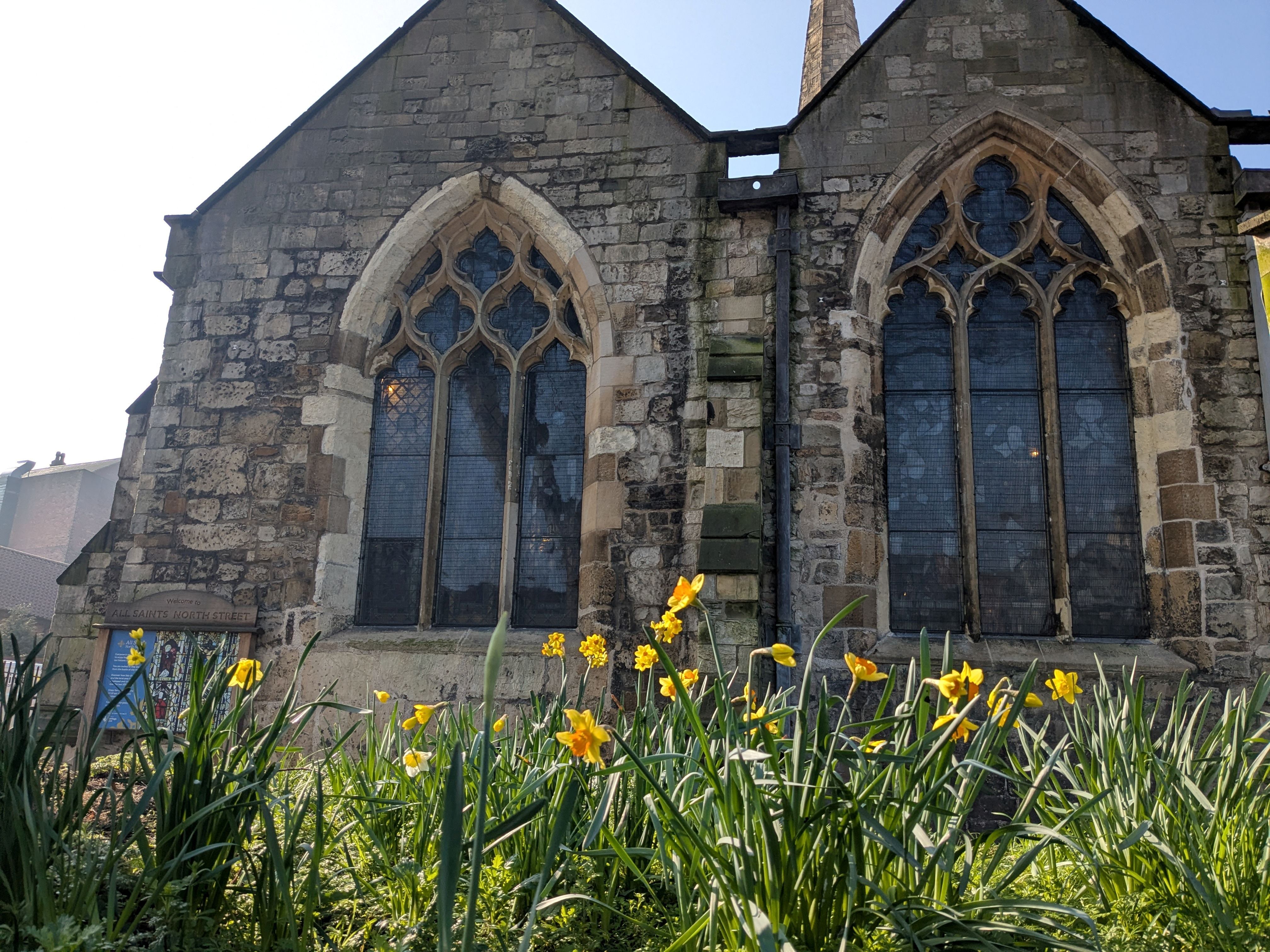 Historic stone church with arched windows and blooming daffodils