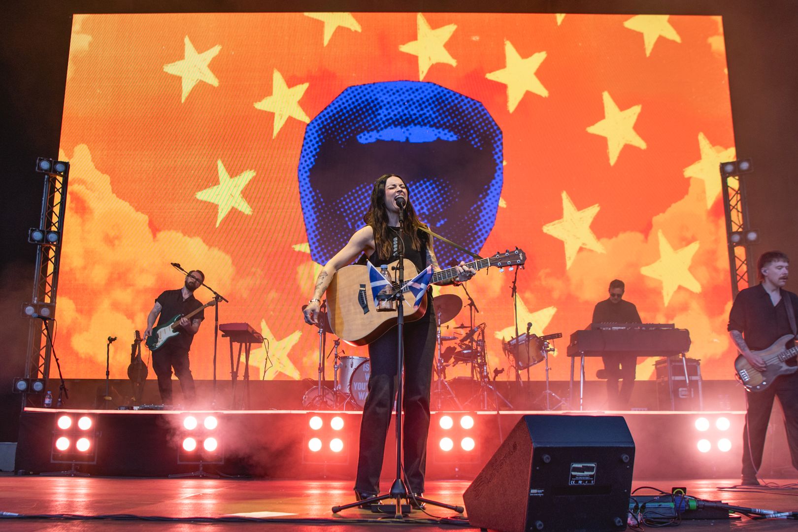 Musician playing guitar on stage with starry backdrop