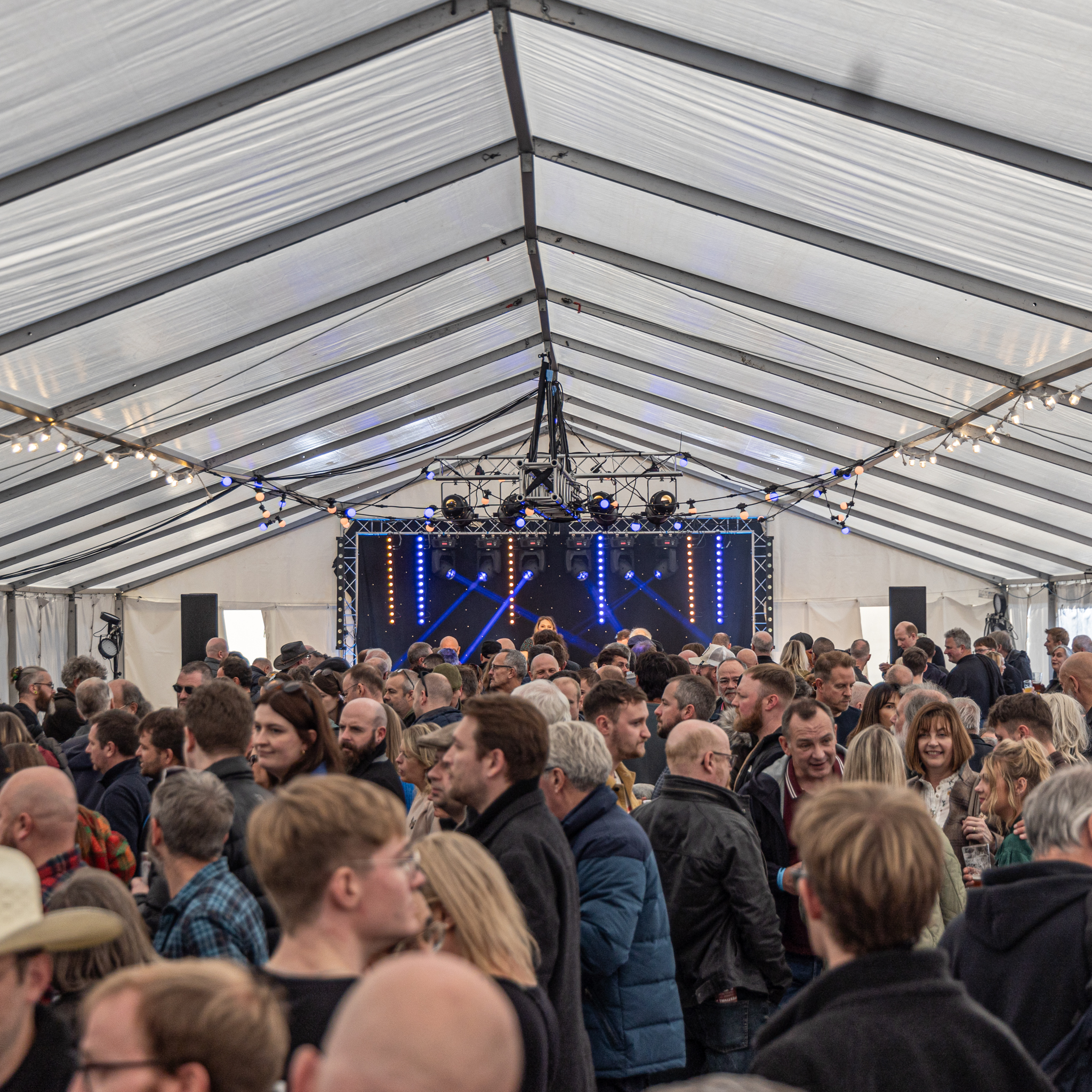 Crowded festival tent with lively audience and stage lighting